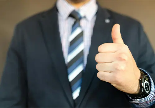 A confident man in business attire giving a thumbs-up, symbolizing success and smart decision-making in Medicare sales strategies.