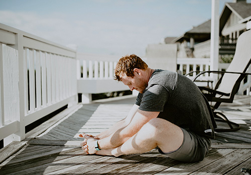 A man takes a break to stretch on his balcony.