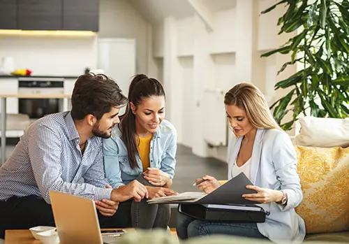 An insurance agent meets with a young couple in their home.
