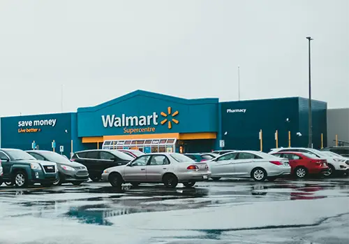 A Walmart parking lot with rain puddles is photographed.