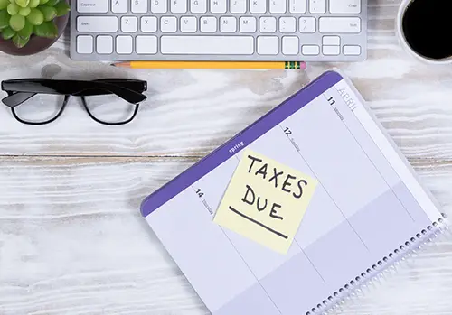 A notebook with a taxes-due message rests on a desk.