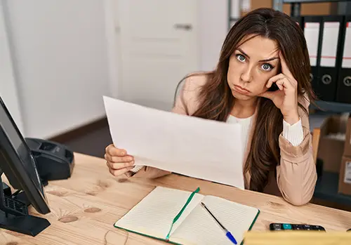 An anxious insurance independent agent sits at her desk and looks directly into the camera.